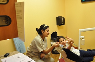 child giving a thumbs up next to dental assistant