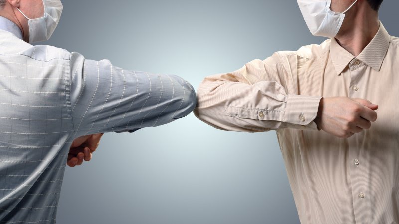 Two men greeting each other using elbow bump