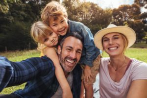 family of four smiling after seeing family dentist 