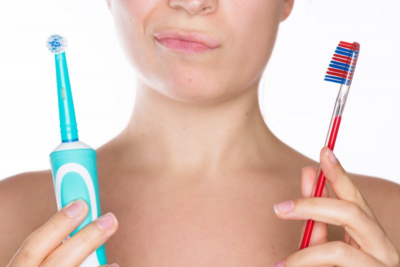 Woman deciding between manual and electric toothbrush
