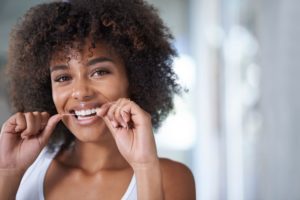 young woman flossing to maintain healthy gums 