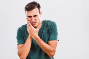 man holding his mouth in pain due to dental emergency 