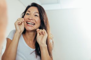 woman flossing in mirror every day