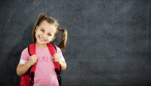 little girl with a backpack smiling after seeing her children’s dentist in Far North Dallas 