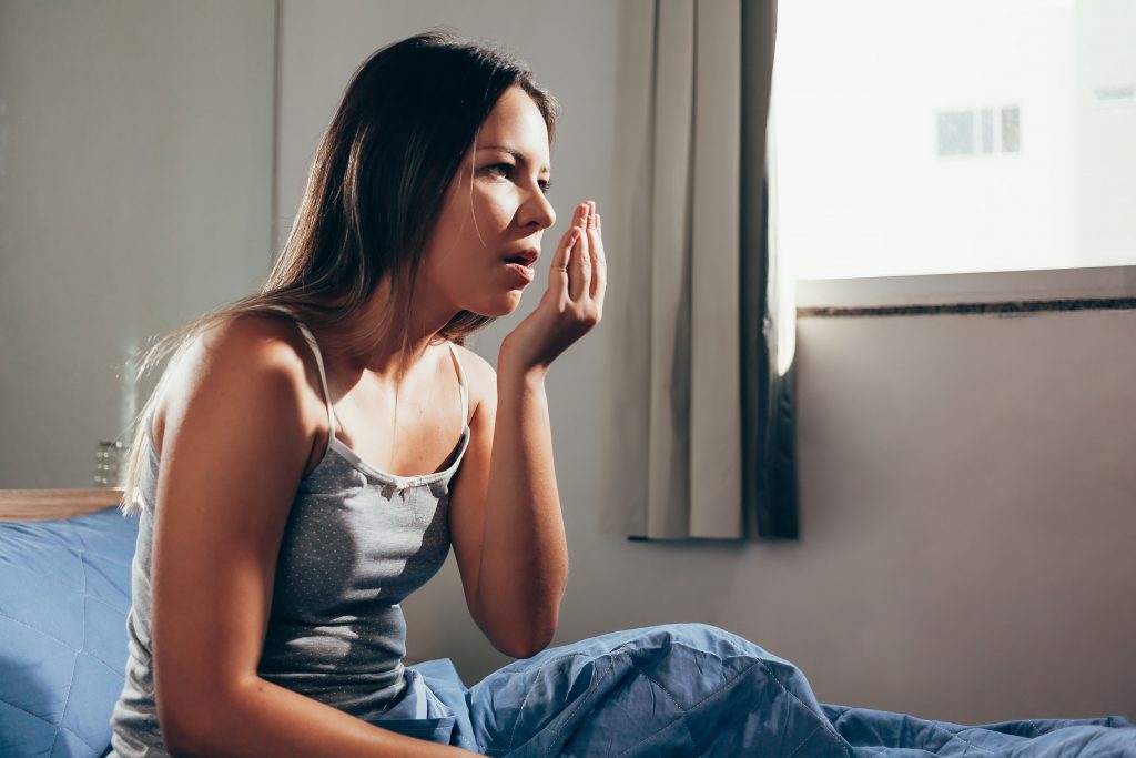 young woman smelling morning breath