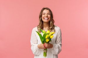a woman with a fresh smile holding spring flowers