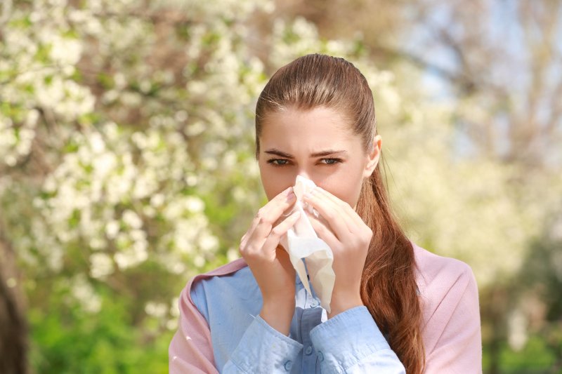 a woman sneezing due to spring allergies in Mesquite