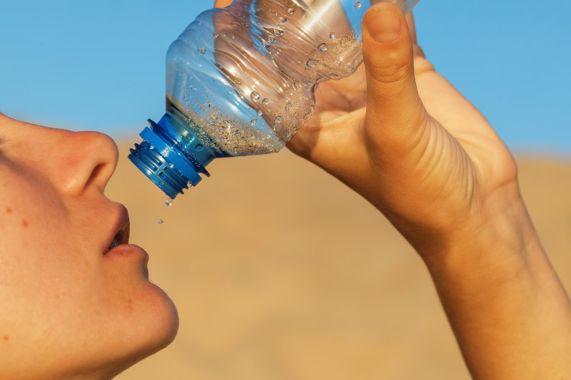Person lifting empty water bottle up to their face
