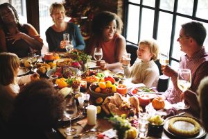 A group of people laughing together over the Thanksgiving table full of food and drinks