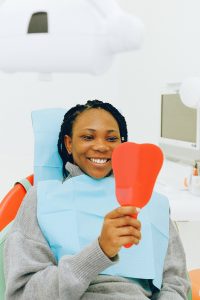 Smiling female dental patient looking in handheld mirror