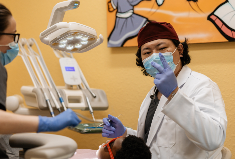 Dentist giving peace sign and performing procedure