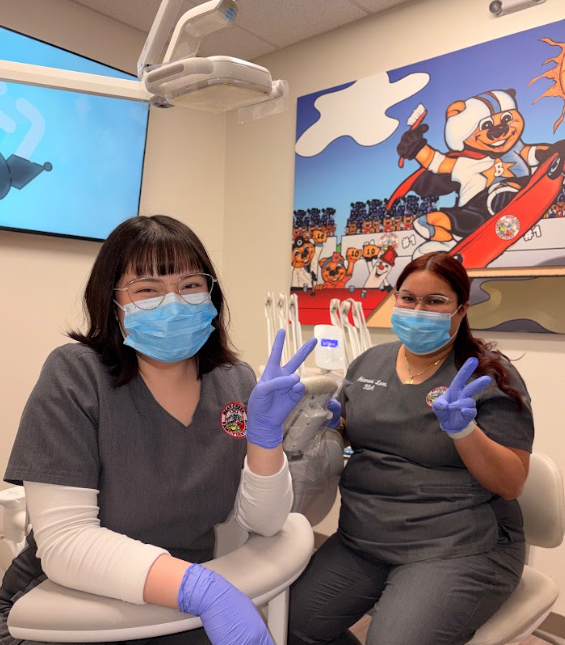 Dental technicians wearing masks and giving peace signs, smiling