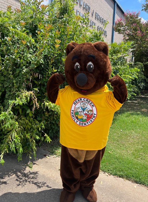 Bear mascot standing outside pumping muscles