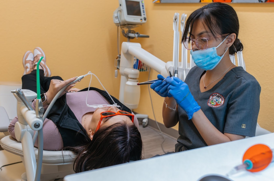 Patient in dental chair with dental assistant holding tool